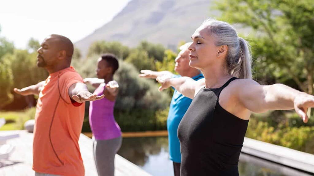 Group of senior people with closed eyes stretching arms outdoor