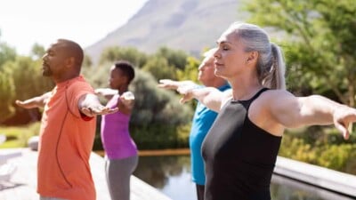 Group of senior people with closed eyes stretching arms outdoor