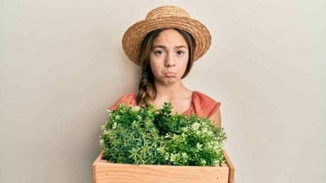 Sad girl holding a box of plants.