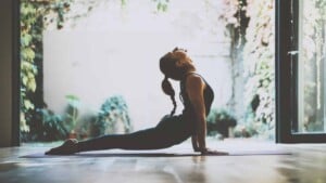 Beautiful girl practicing the cobra asana yoga pose in class.