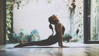 Beautiful girl practicing the cobra asana yoga pose in class.