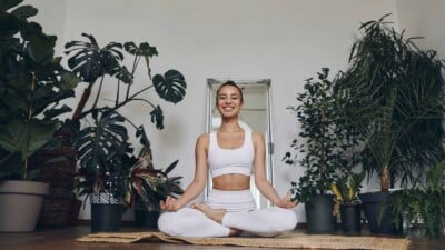 Woman doing yoga in a room full of common house plants.