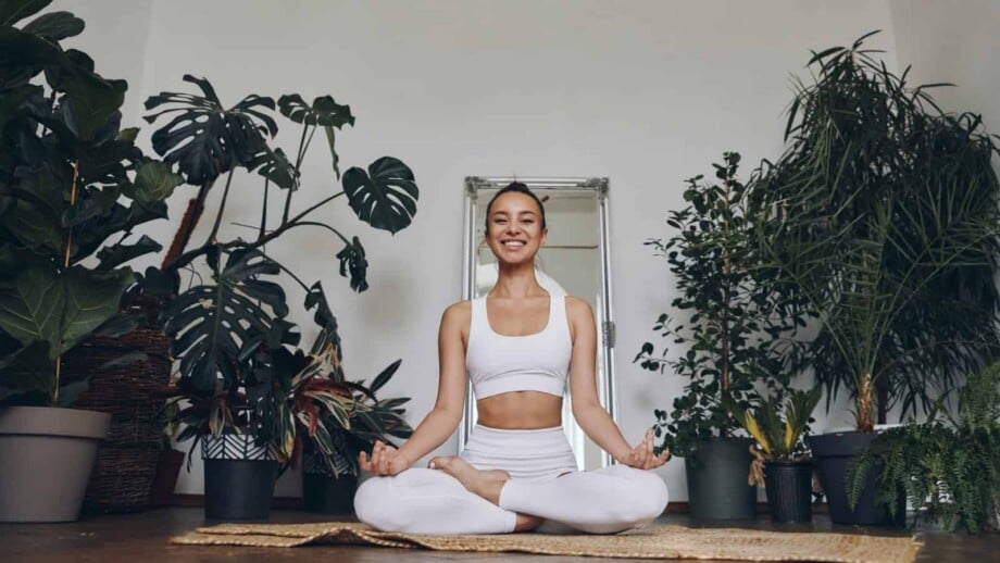 Woman doing yoga in a room full of common house plants.