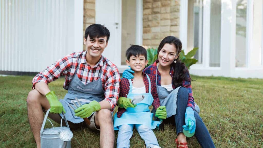 Asian family sitting together with gardening gloves on, ready to work in the garden
