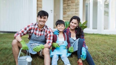 Asian family sitting together with gardening gloves on, ready to work in the garden