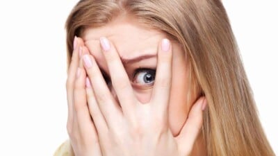 Scared woman looking through fingers