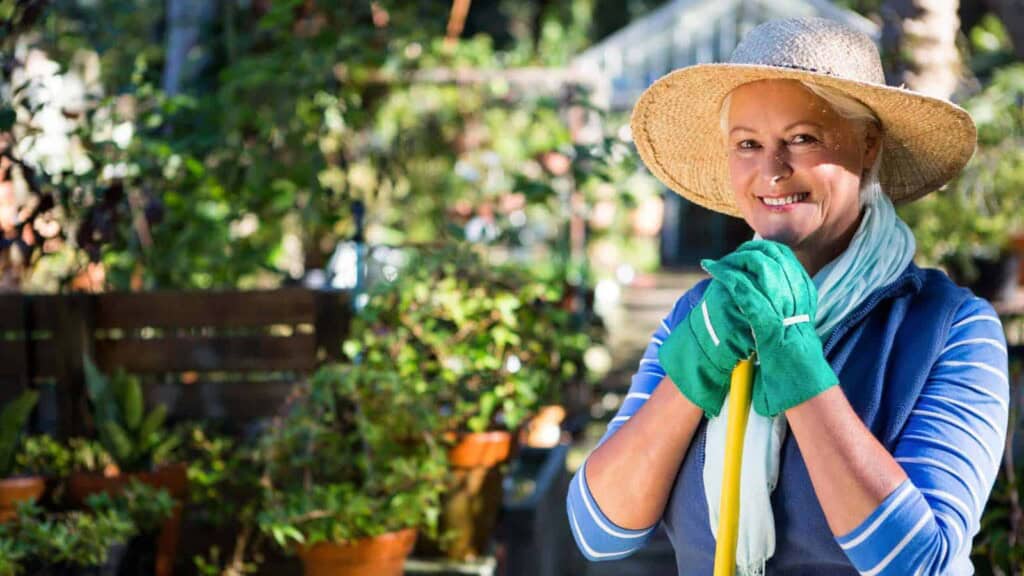 Senior female gardener in hat smiling in her garden
