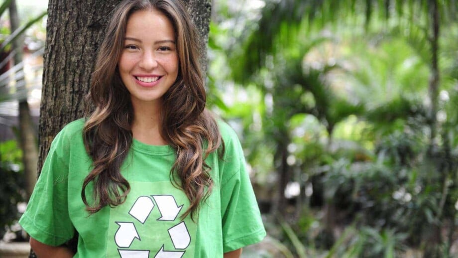 young female environmental activist in the forest wearing a green recycle t-shirt