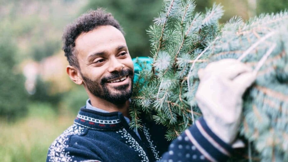 Happy man carrying a Christmas Tree